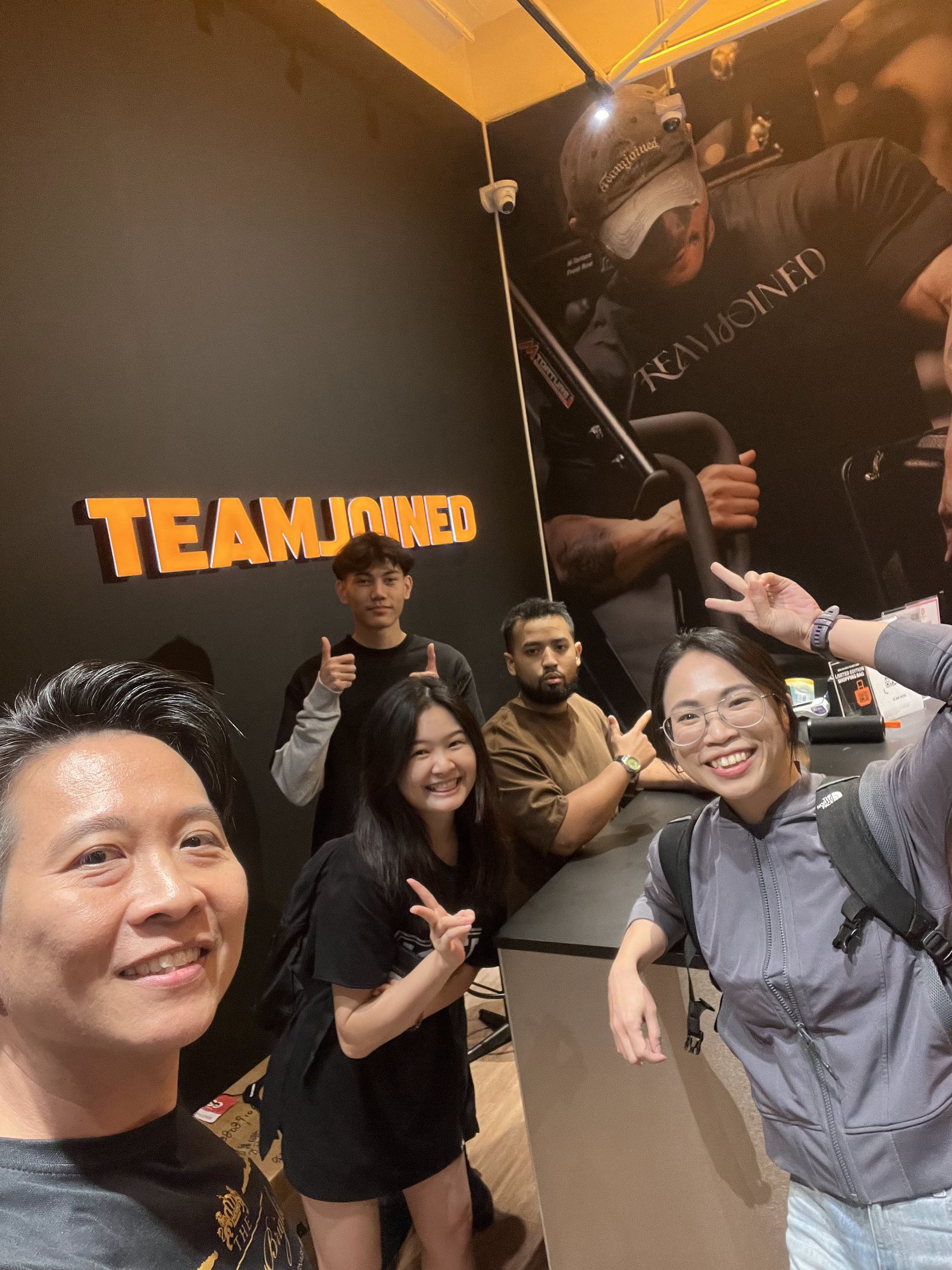 A group selfie with the TeamJoined staff in Malaysia, under the TeamJoined sign